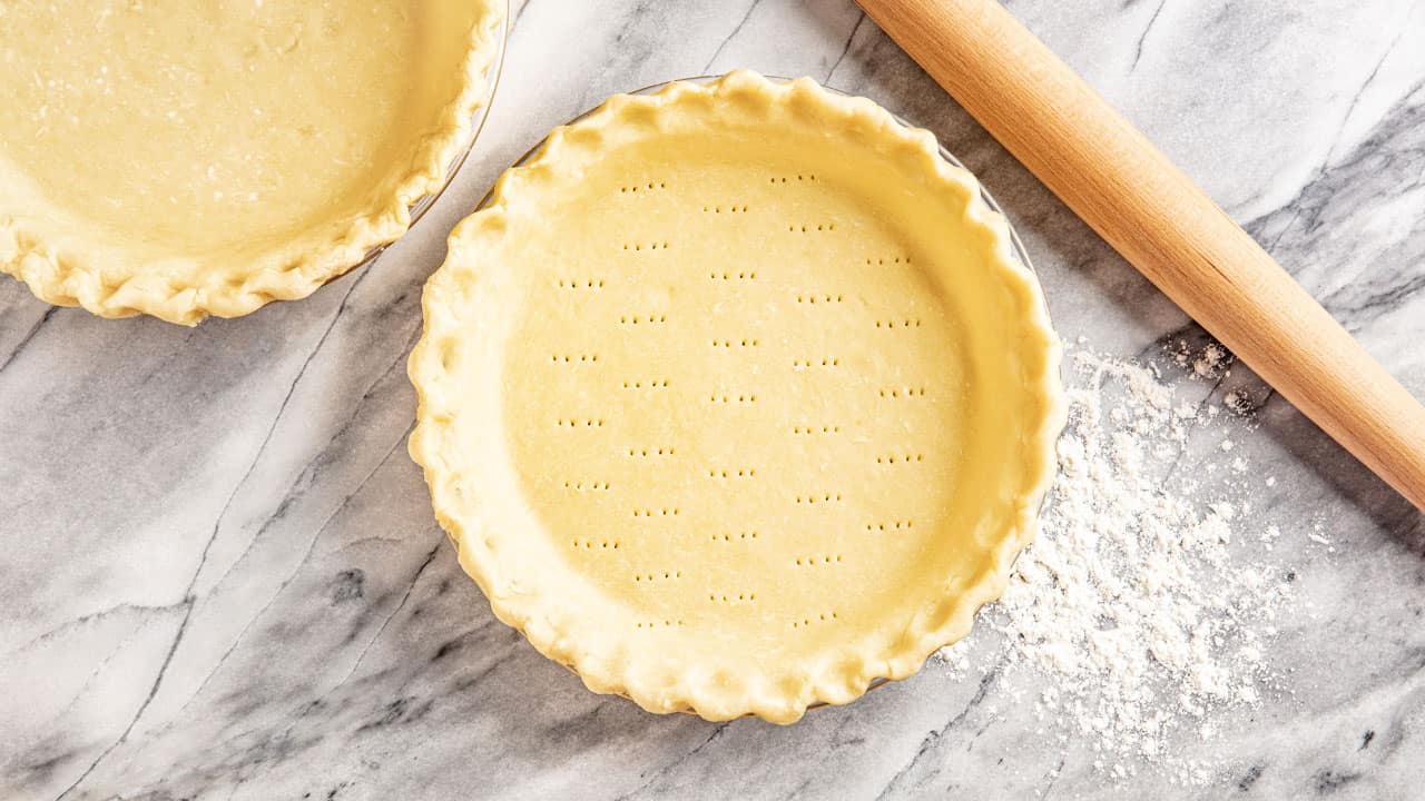 Bird's eye view of Pie Crust perforated by a fork in a glass pie dish.