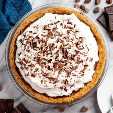 Bird's eye view of a chocolate cream pie surrounded by pieces of chocolate