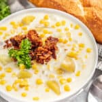 Corn chowder topped with bacon and parsley in a white bowl