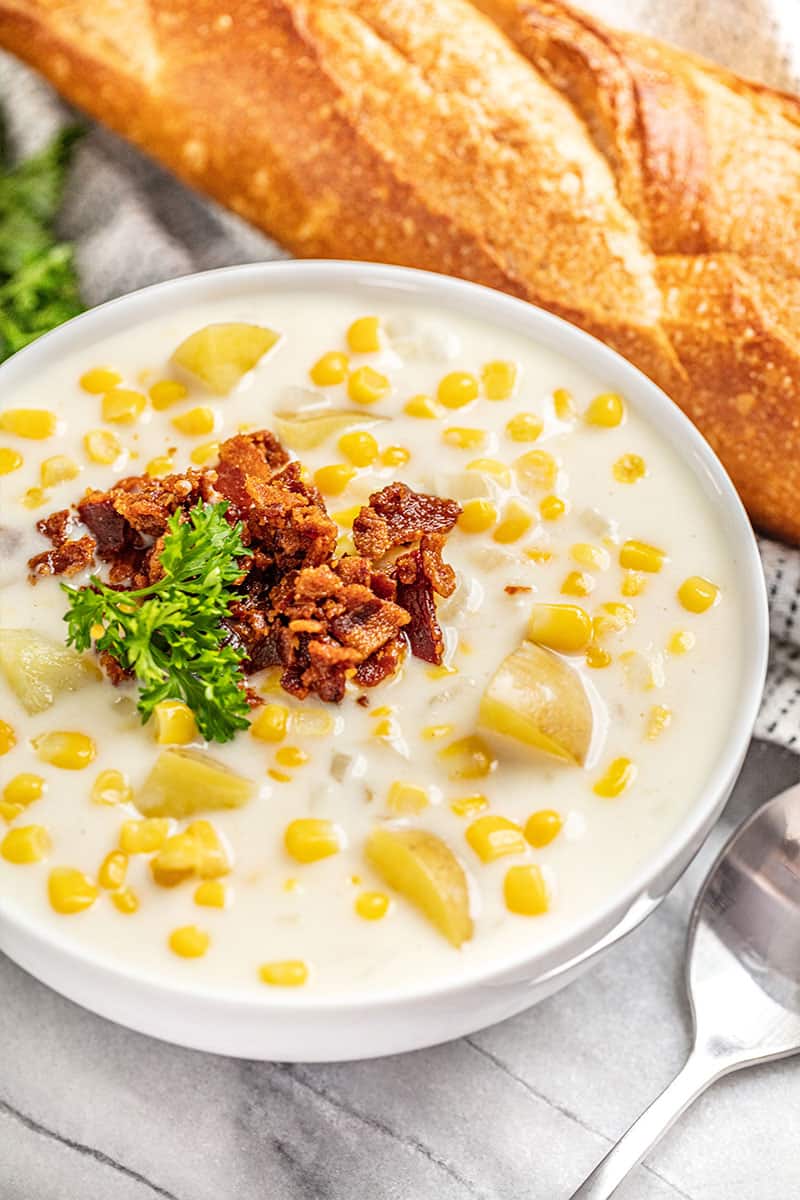 Corn chowder topped with bacon and parsley in a white bowl