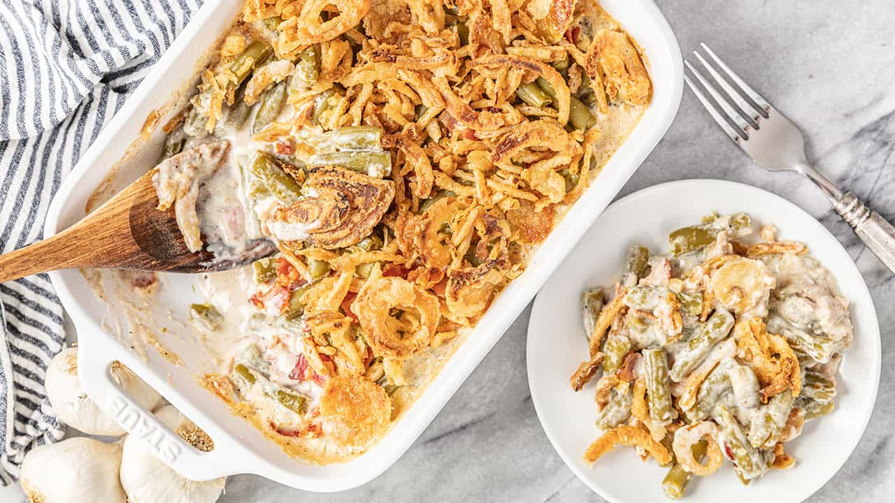 Bird's eye view of a serving of Green Bean Casserole with bacon and crunchy fried onion that has been scooped from the pan and placed on a serving plate