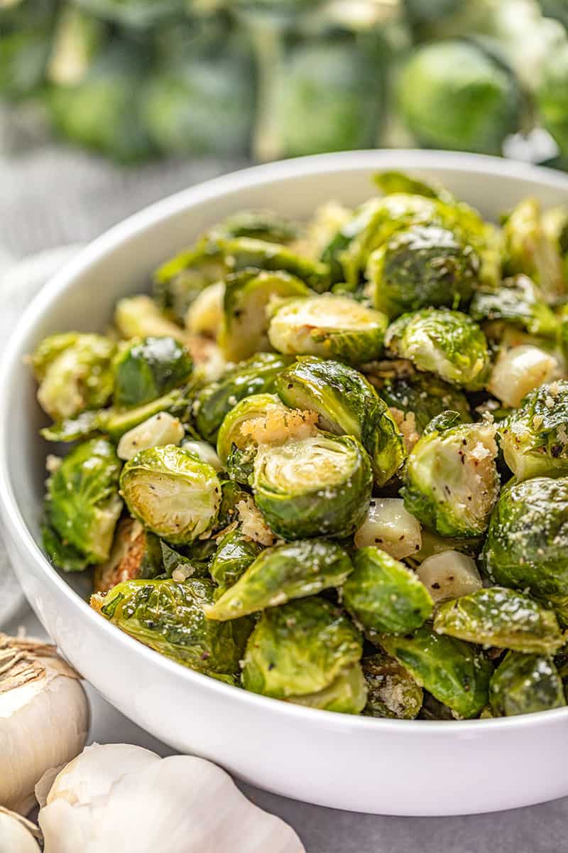 Garlic Butter Roasted Brussel Sprouts  tossed with parmesan cheese in a white bowl.