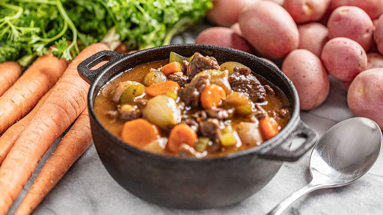 Angled view of a single serving of beef stew served in a cast iron bowl.