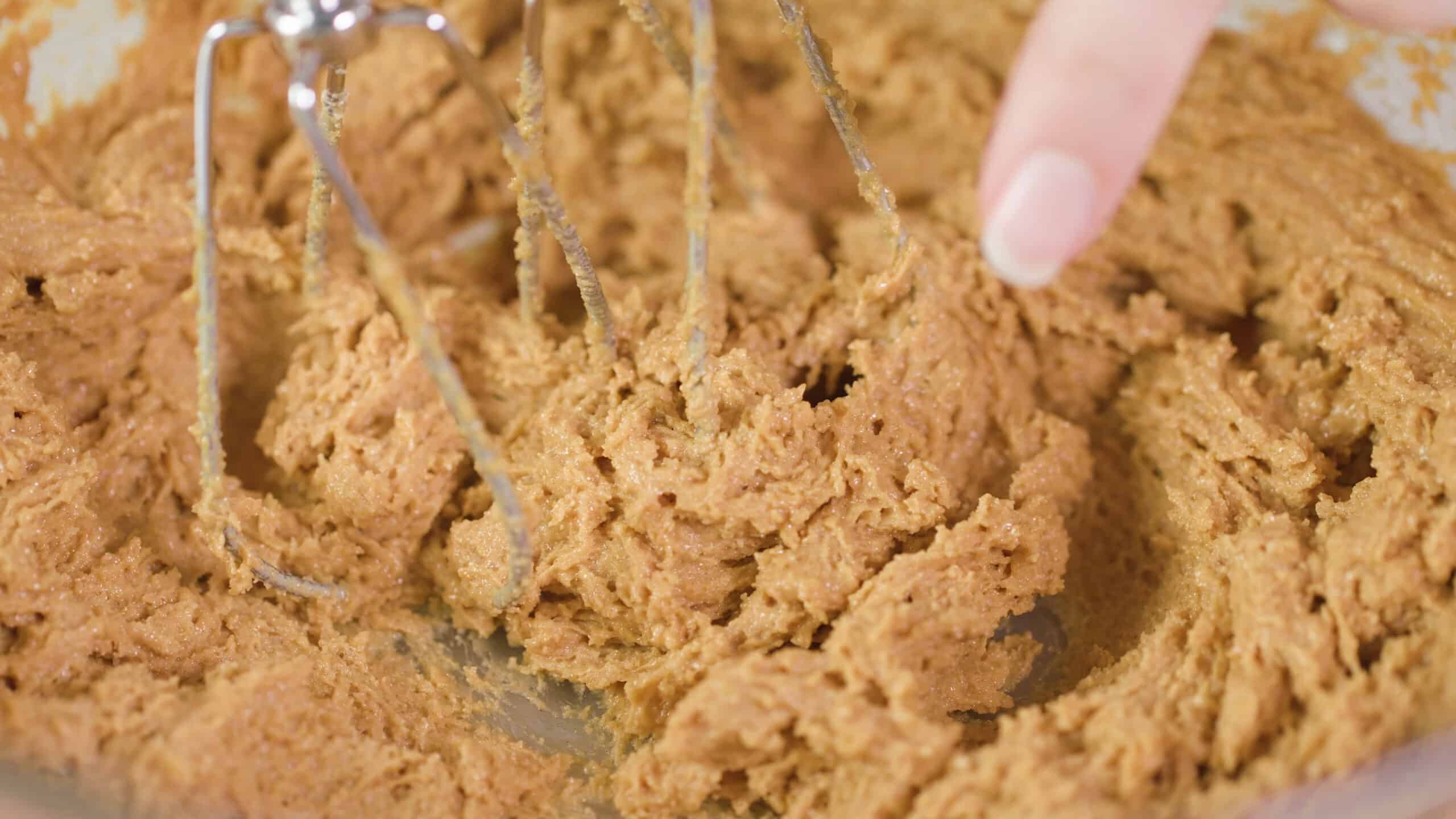 Close-up view of peanut butter cookie dough to show texture after beating ingredients together with hand mixer.