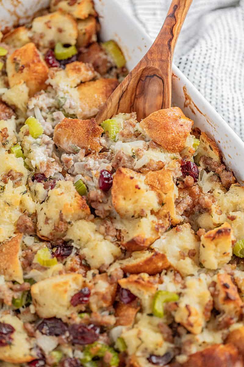 Sausage Stuffing in a white dish with a wooden spoon in it.