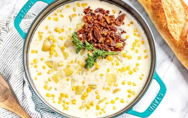 Bird's eye view of Corn chowder topped with bacon and parsley in a large cast iron pot.