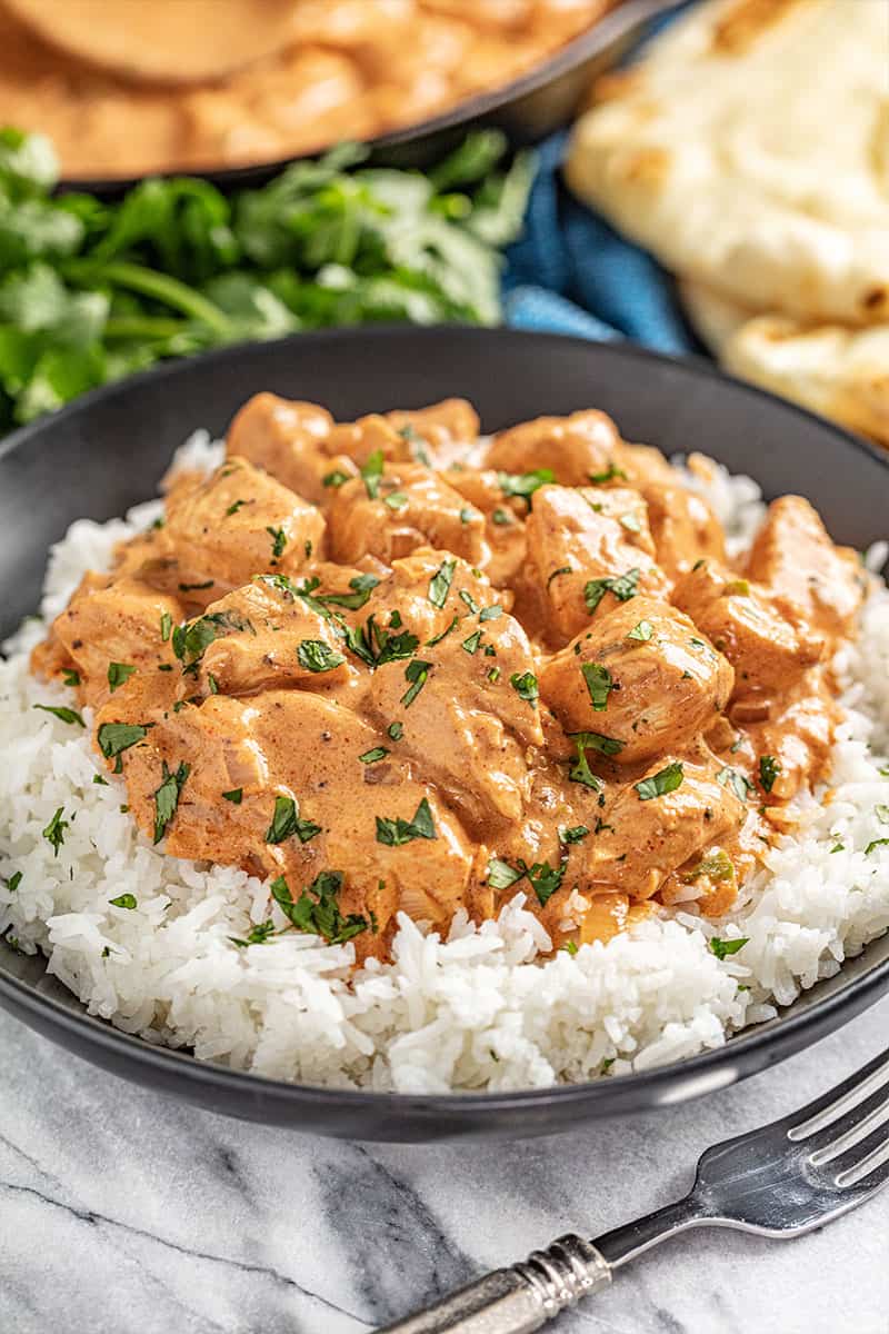 Butter chicken and white rice in black bowl