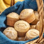 Banana muffins in a basket with bananas in the background