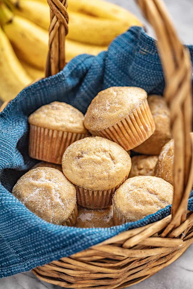 Banana muffins in a basket with bananas in the background