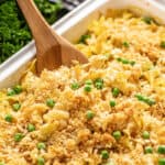 Creamy chicken casserole in white baking dish with wooden spoon.