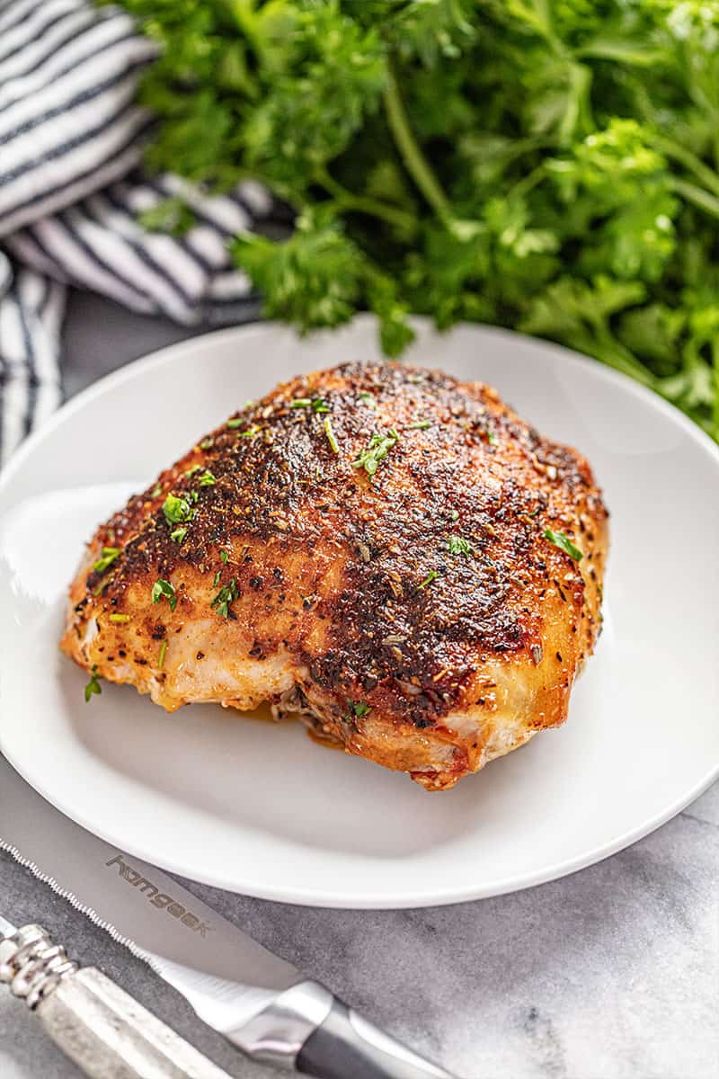 Crispy oven baked chicken thigh on white plate