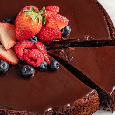 Flourless chocolate cake with berries on top and a slice cut out