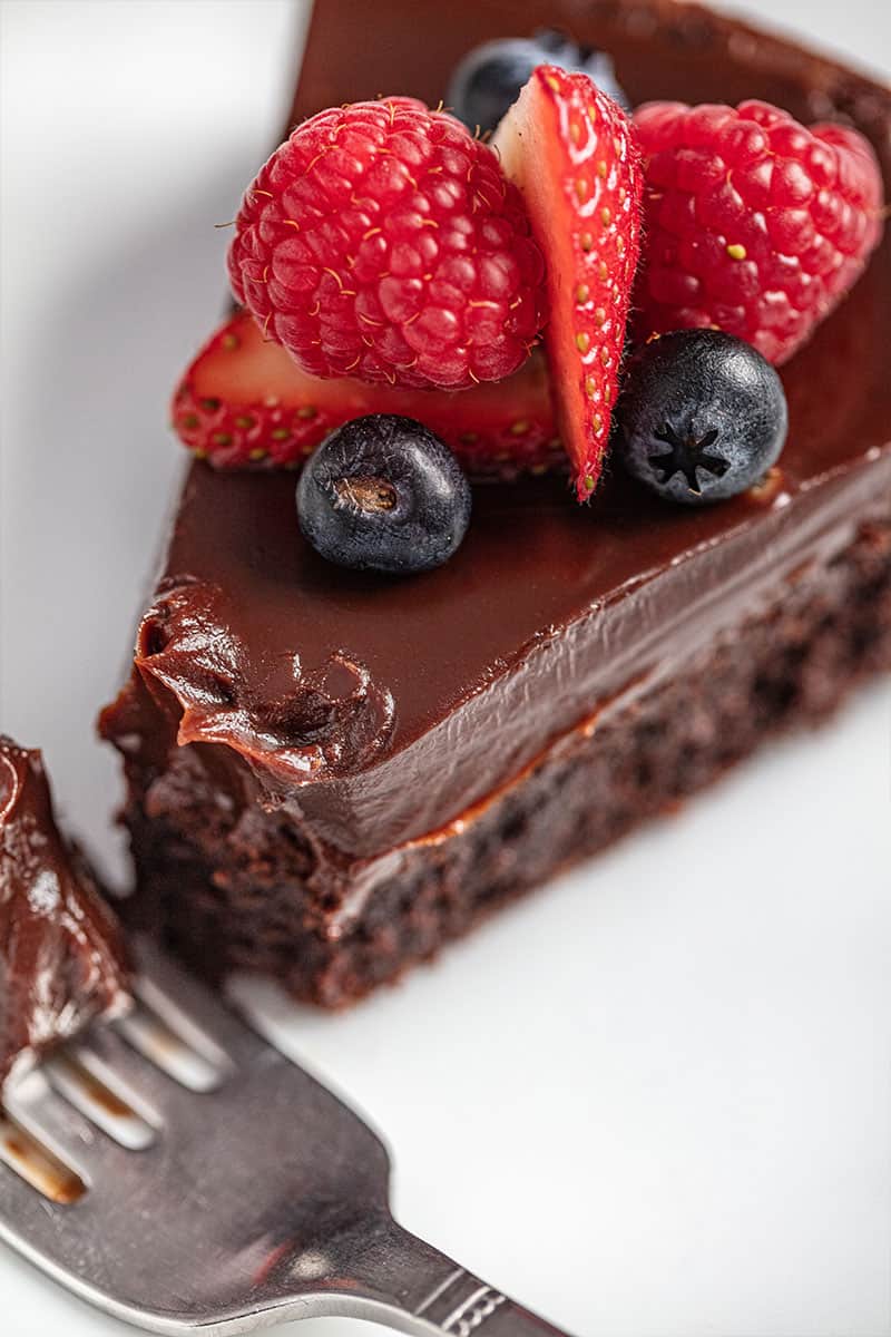 Flourless chocolate cake with a bite taken out of it on a white plate with a fork.