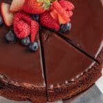 Flourless chocolate cake with berries on top and a slice cut out