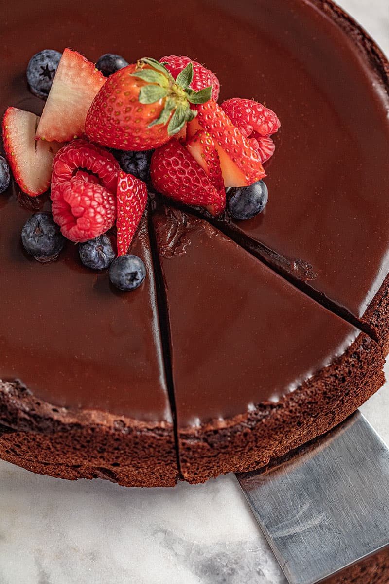 Bird's eye view of a flourless chocolate cake with a slice being taken out of it.