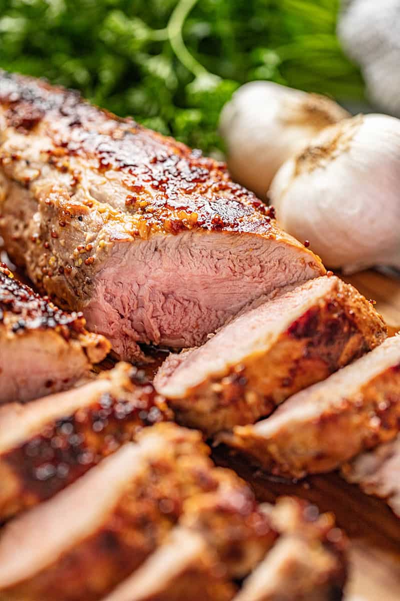 Close up of a juicy and tender Honey Dijon Garlic Roasted Pork Tenderloin, cut into slices