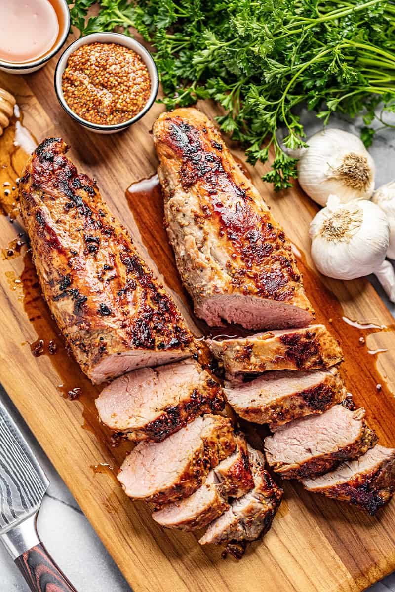 Sliced Roasted Pork Tenderloin with the juices running out on a cutting board. 