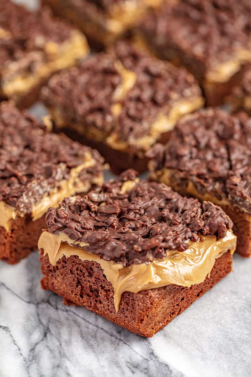 Peanut butter crunch brownies on a marble countertop cut into squares.