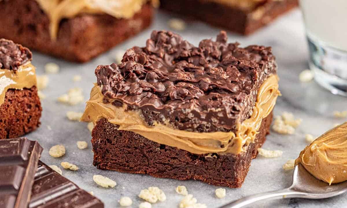 Peanut butter crunch brownies with spoonful of peanut butter and chocolate pieces