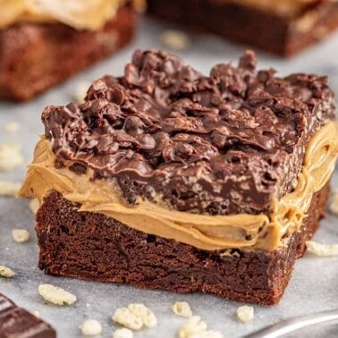 Peanut butter crunch brownies with spoonful of peanut butter and chocolate pieces