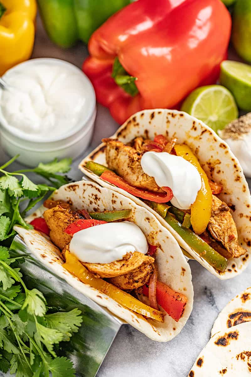 Chicken Fajitas in flour tortillas with multi colored bell peppers and onion and topped with sour cream