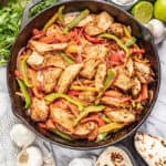 Chicken Fajitas in a cast iron skillet with multi colored bell peppers and onion