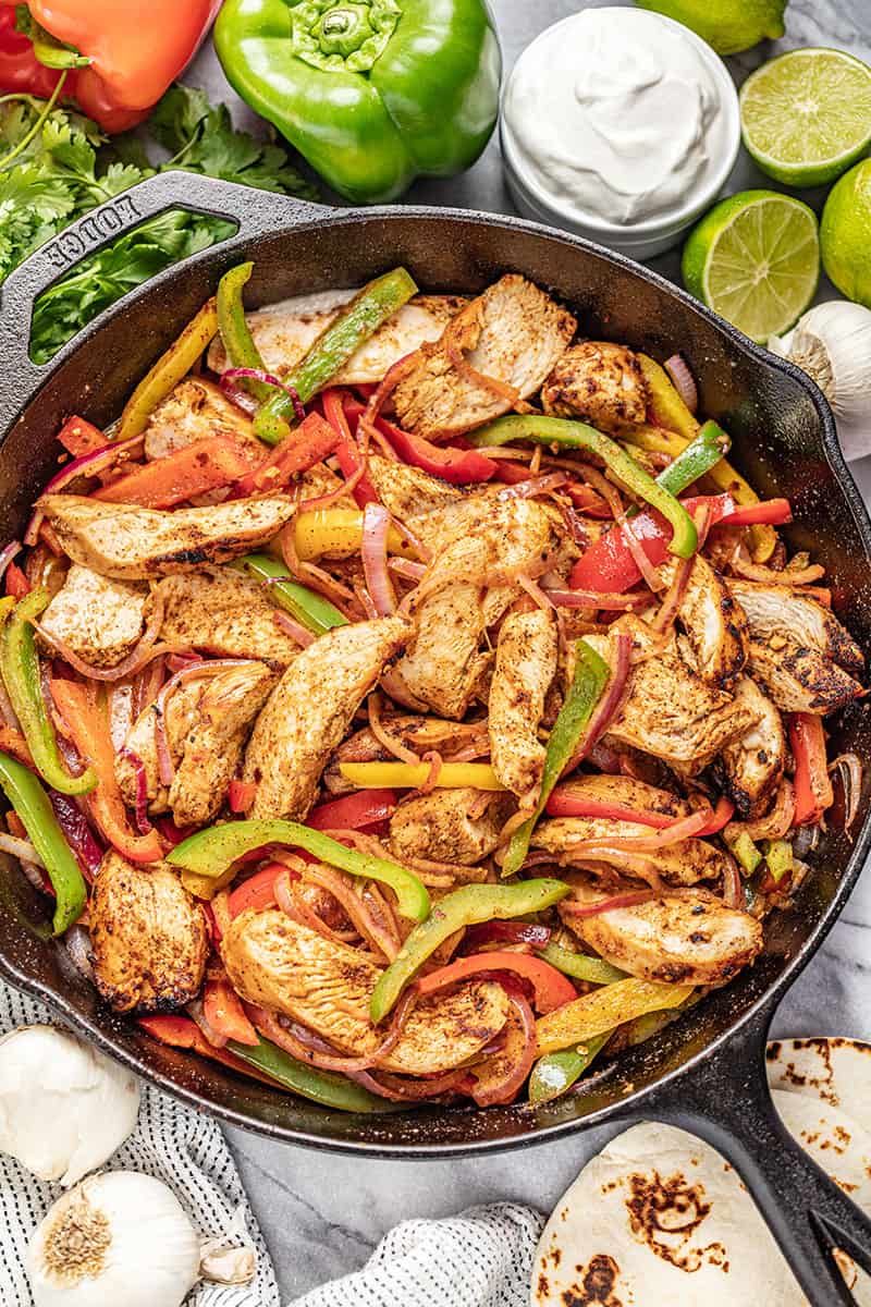 Chicken Fajitas in a cast iron skillet with multi colored bell peppers and onion