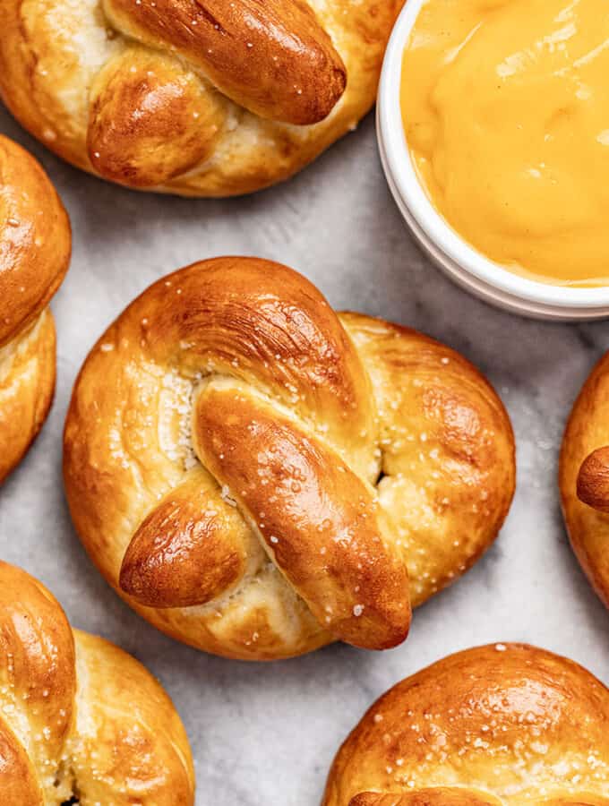 Homemade soft pretzels on a baking sheet with a cup of cheese dip