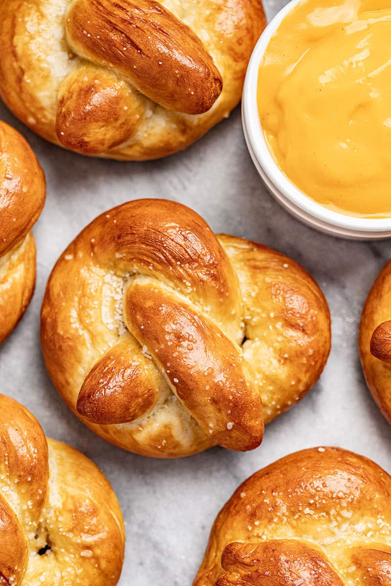 Homemade soft pretzels on a baking sheet with a cup of cheese dip