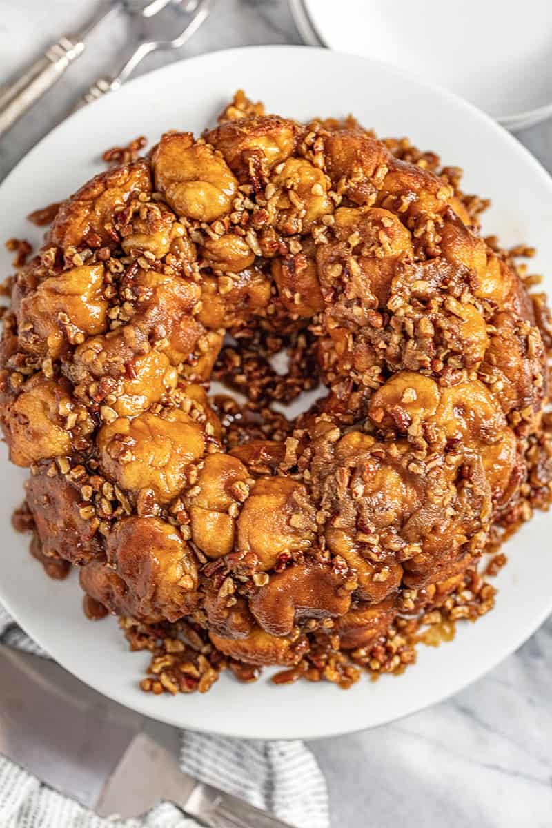 Gooey caramel pecan monkey bread on a white cake plate.