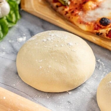 Italian style pizza dough balls next to a baked pizza