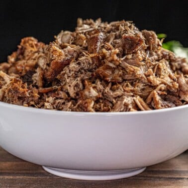 Crockpot carnitas in white bowl.