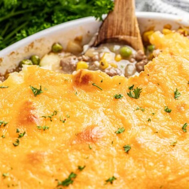 Old fashioned shepherds pie in a baking dish with a wooden spoon