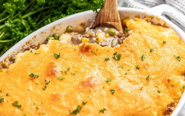 Old fashioned shepherds pie in a baking dish with a wooden spoon