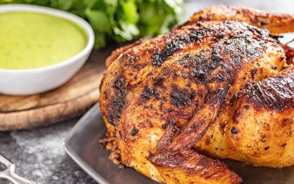 Oven roasted Peruvian chicken on a platter with green dipping sauce