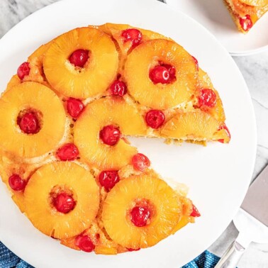 Pineapple Upside Down Cake with a piece cut out on a white cake plate
