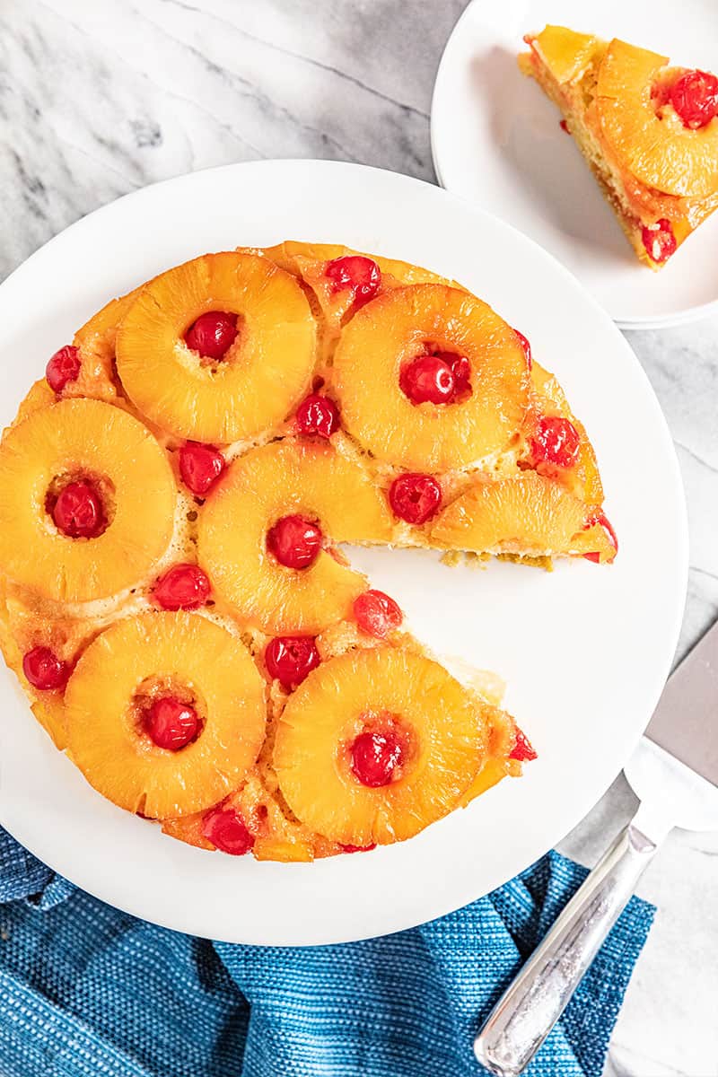 Pineapple Upside Down Cake with a piece cut out on a white cake plate