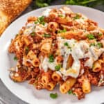 A serving of baked ziti sprinkled with parsley on a white plate