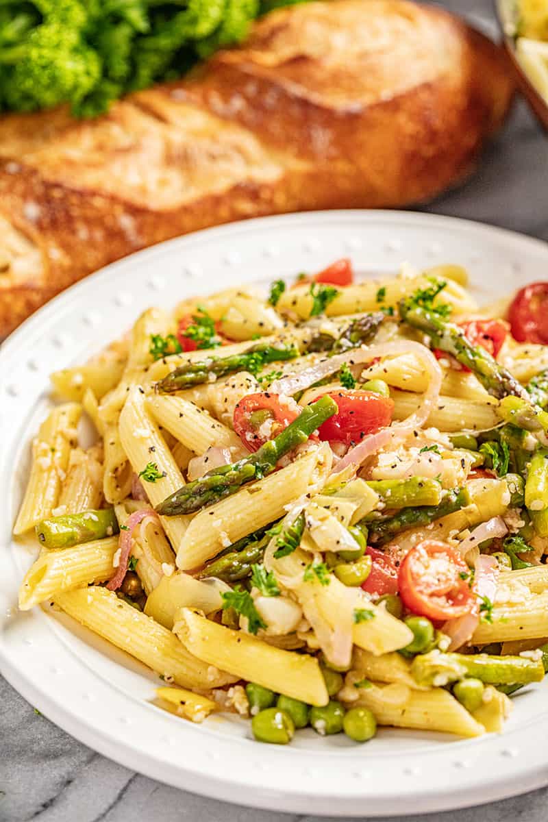 A serving of creamy pasta primavera on white plate