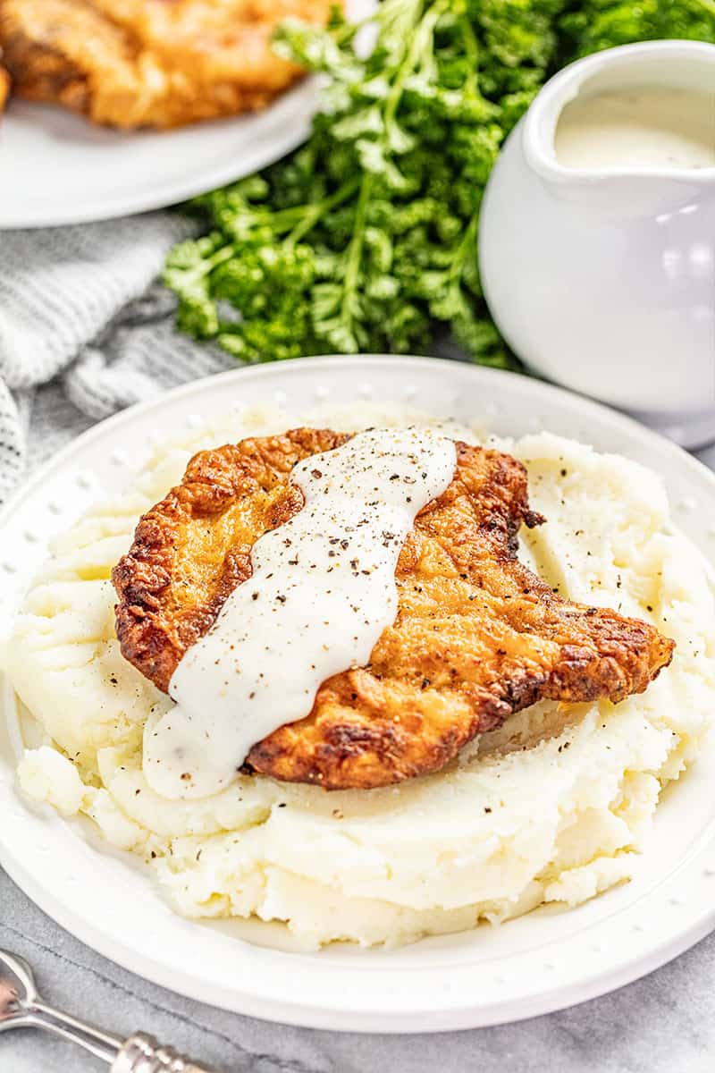 Crispy fried pork chop with gravy on bed of mashed potatoes