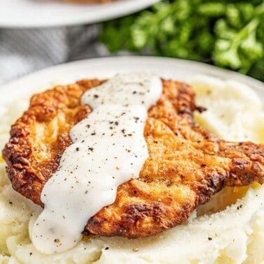 Crispy fried pork chop with gravy on bed of mashed potatoes