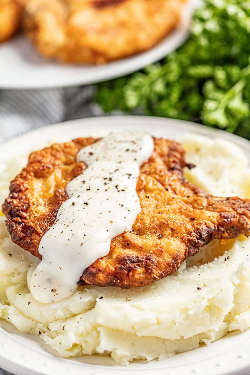 Crispy fried pork chop with gravy on bed of mashed potatoes