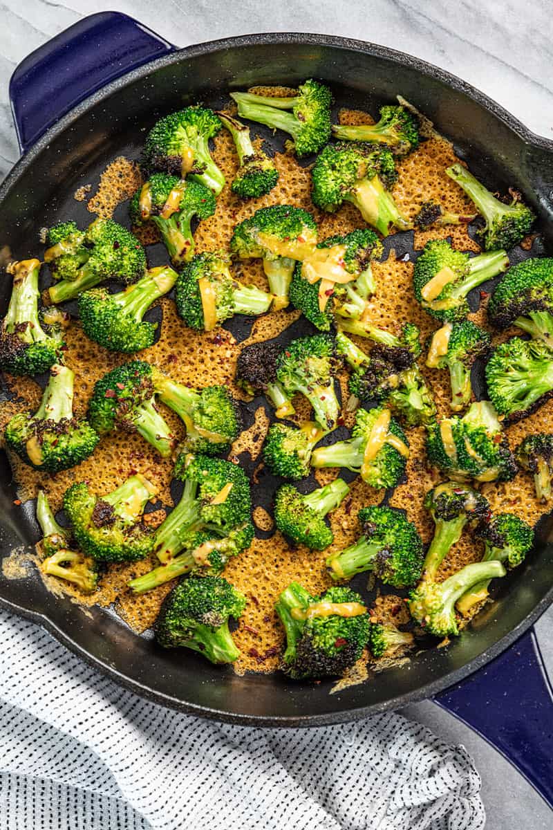 Cheesy broccoli in a blue skillet.