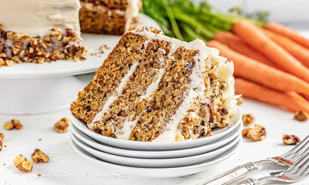 A stack of carrot cake on its side on a stack of white plates
