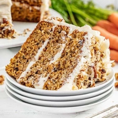 A stack of carrot cake on its side on a stack of white plates
