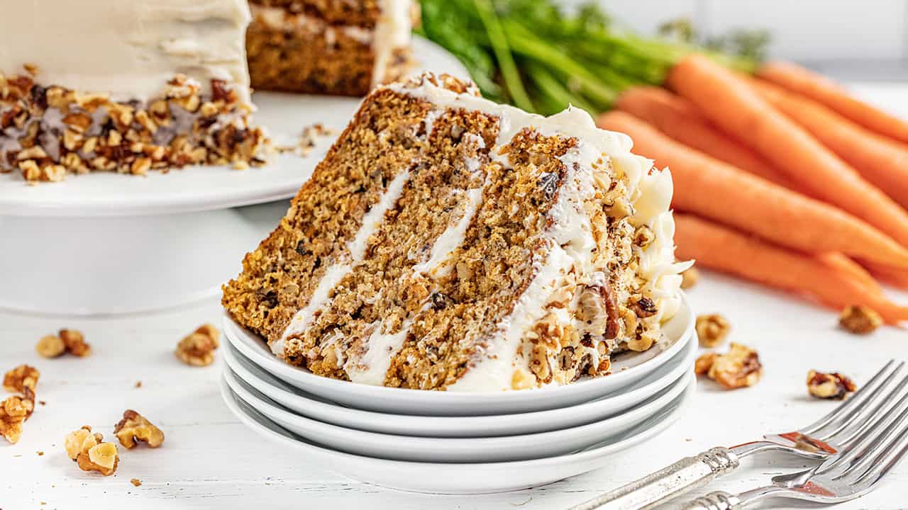 A stack of carrot cake on its side on a stack of white plates