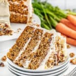 A slice of carrot cake on its side on a stack of white plates