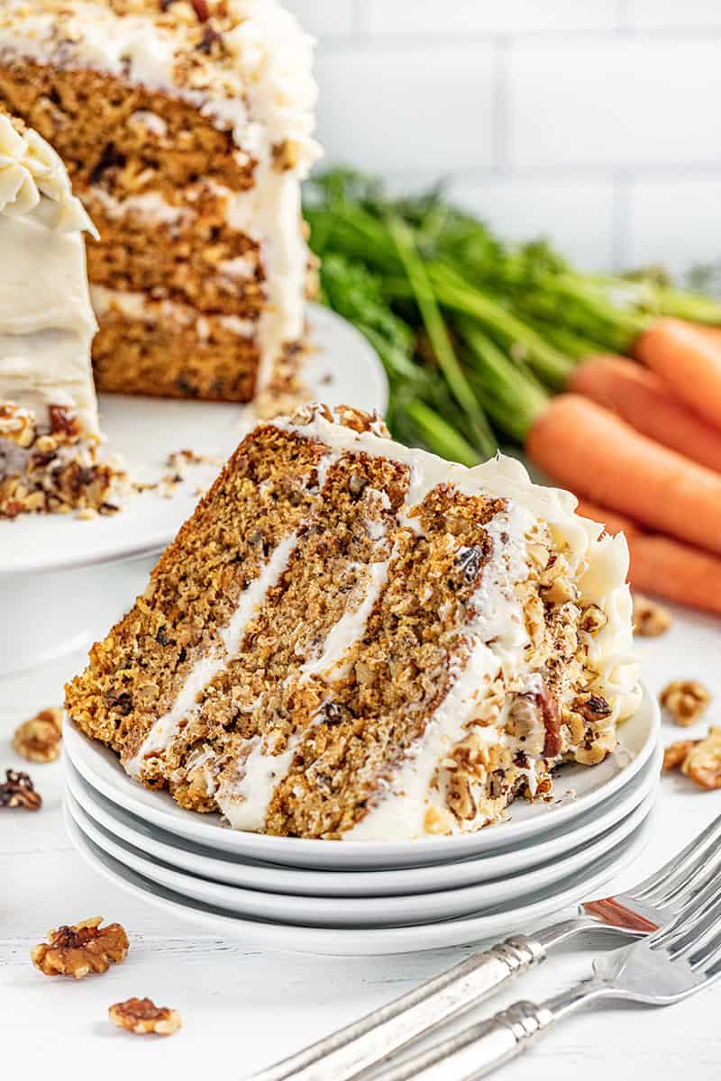 A slice of carrot cake on its side on a stack of white plates