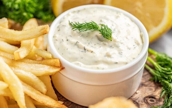 Homemade tartar sauce in a white serving bowl with chips on the side
