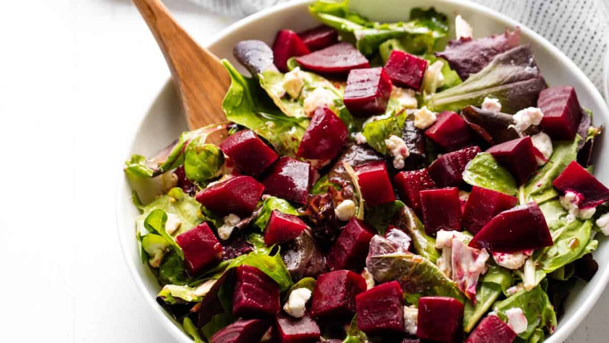 Beet salad in a bowl with a wooden spoon